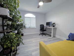 Home office with light wood-style floors and a ceiling fan