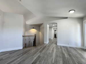 Spare room with light wood-style flooring, arched walkways, and vaulted ceiling