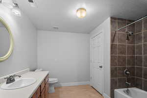 Bathroom with light wood-style floors, shower / washtub combination, vanity, and a textured ceiling