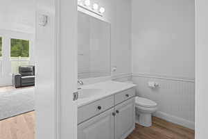 Bathroom featuring light wood-style floors, vanity, and a wainscoted wall
