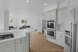 Kitchen with stainless steel appliances, recessed lighting, light wood finished floors, open floor plan, and a kitchen bar