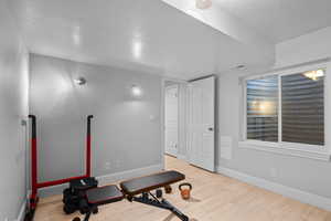 Exercise room featuring light wood finished floors and a textured ceiling