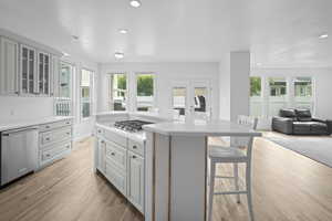 Kitchen with stainless steel appliances, open floor plan, a breakfast bar, a center island, and light wood-type flooring