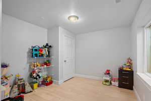 Game room with light wood-style flooring and a textured ceiling