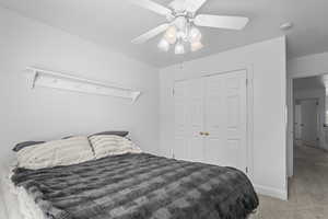 Bedroom with light colored carpet, a closet, and a ceiling fan