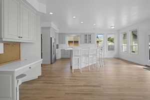 Kitchen with a kitchen bar, light wood-style floors, recessed lighting, light countertops, and high end fridge