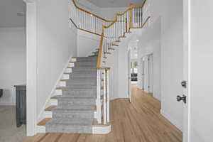 Stairs with wood finished floors and a high ceiling