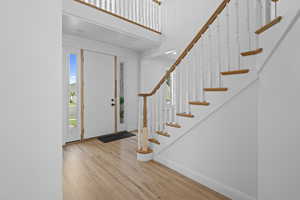 Entrance foyer with light wood-type flooring, stairs, and a towering ceiling
