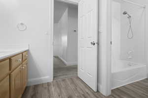 Bathroom featuring shower / bathtub combination, vanity, and light wood-style floors