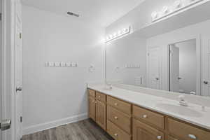 Bathroom featuring double vanity and dark wood-type flooring
