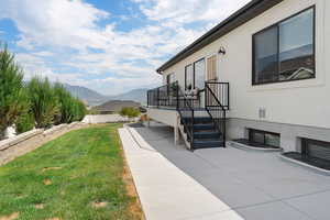 View of side of property featuring a patio area, a mountain view, and stucco siding