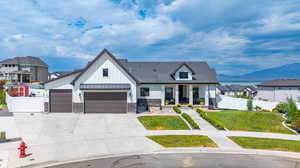 Modern inspired farmhouse featuring board and batten siding, a porch, stone siding, a mountain and lake view, and driveway
