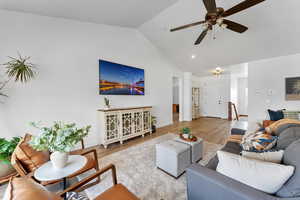 Living room with wood tile finished floors, a ceiling fan, and high vaulted ceiling