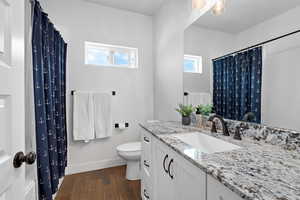 Full bath with dark wood-type flooring, vanity, granite counters and a shower with curtain