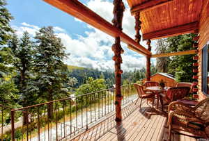 Wooden terrace with outdoor dining area and a forest view