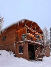 Snow covered property with stairway and a wooden deck