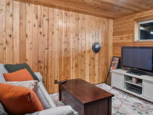 Living room featuring wooden ceiling and wood walls