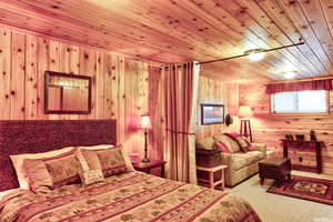 Bedroom featuring wood walls, wooden ceiling, and carpet