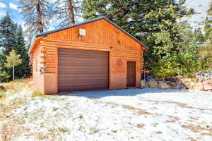 Snow covered garage featuring a detached garage