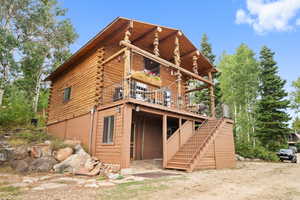 Rear view of house with stairs, log siding, and a wooden deck