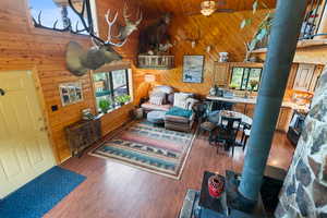 Living room featuring wood finished floors, ceiling fan, wood walls, a high ceiling, and wood ceiling