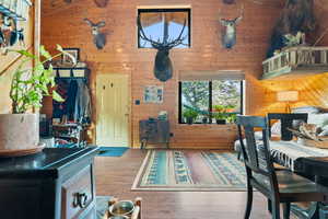 Bedroom with wooden walls, wood finished floors, a wooden ceiling with exposed beams, and high vaulted ceiling