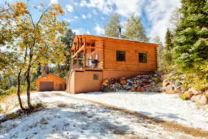 Log home with log siding, an outbuilding, a garage, and a balcony