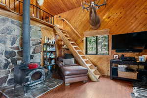 Living room featuring a wood stove, wood finished floors, wooden walls, and wooden ceiling