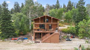 Cabin with a deck, log exterior, stairway, and a wooded view