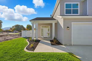 View of exterior entry featuring a garage and a shingled roof