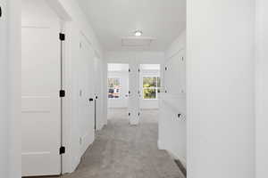 Hallway featuring light carpet, attic access, and an upstairs landing