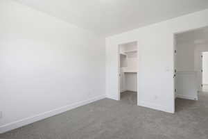 Unfurnished bedroom with carpet and a spacious closet