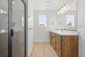 Bathroom with vanity, healthy amount of natural light, light wood finished floors, and a stall shower