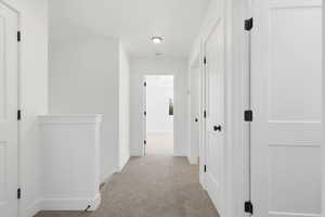 Hall featuring light colored carpet and an upstairs landing