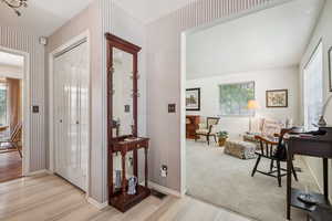 Entrance foyer featuring wallpapered walls, light wood-style flooring, and light colored carpet