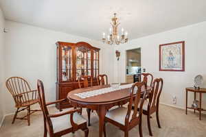 Dining area with light carpet and a chandelier
