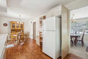 Kitchen featuring a chandelier, freestanding refrigerator, decorative light fixtures, and dark wood-type flooring