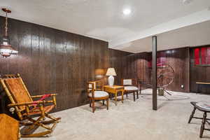 Sitting room featuring carpet, wood walls, and a textured ceiling
