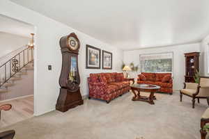 Carpeted living area with a chandelier and stairs