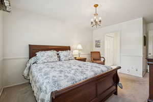 Bedroom with light carpet, a chandelier, and a closet