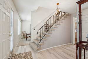 Foyer with light wood-type flooring, a chandelier, and stairs