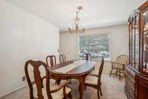 Dining space with light colored carpet and a chandelier
