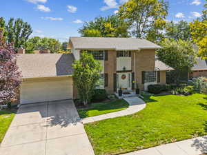 View of front of property featuring a garage, a shingled roof, concrete driveway, and brick siding