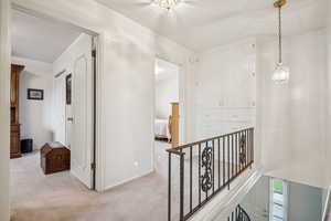 Corridor with light colored carpet and an upstairs landing