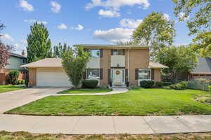 View of front of home with an attached garage, driveway, and brick siding