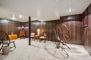 Living area featuring carpet flooring, wood walls, a textured ceiling, and recessed lighting