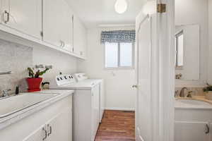 Laundry room featuring dark wood finished floors, separate washer and dryer, and cabinet space