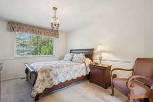 Carpeted bedroom featuring a chandelier and baseboards