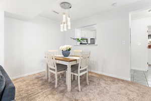 Dining area with light colored carpet and ornamental molding