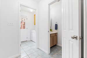 Corridor featuring light tile patterned floors and separate washer and dryer